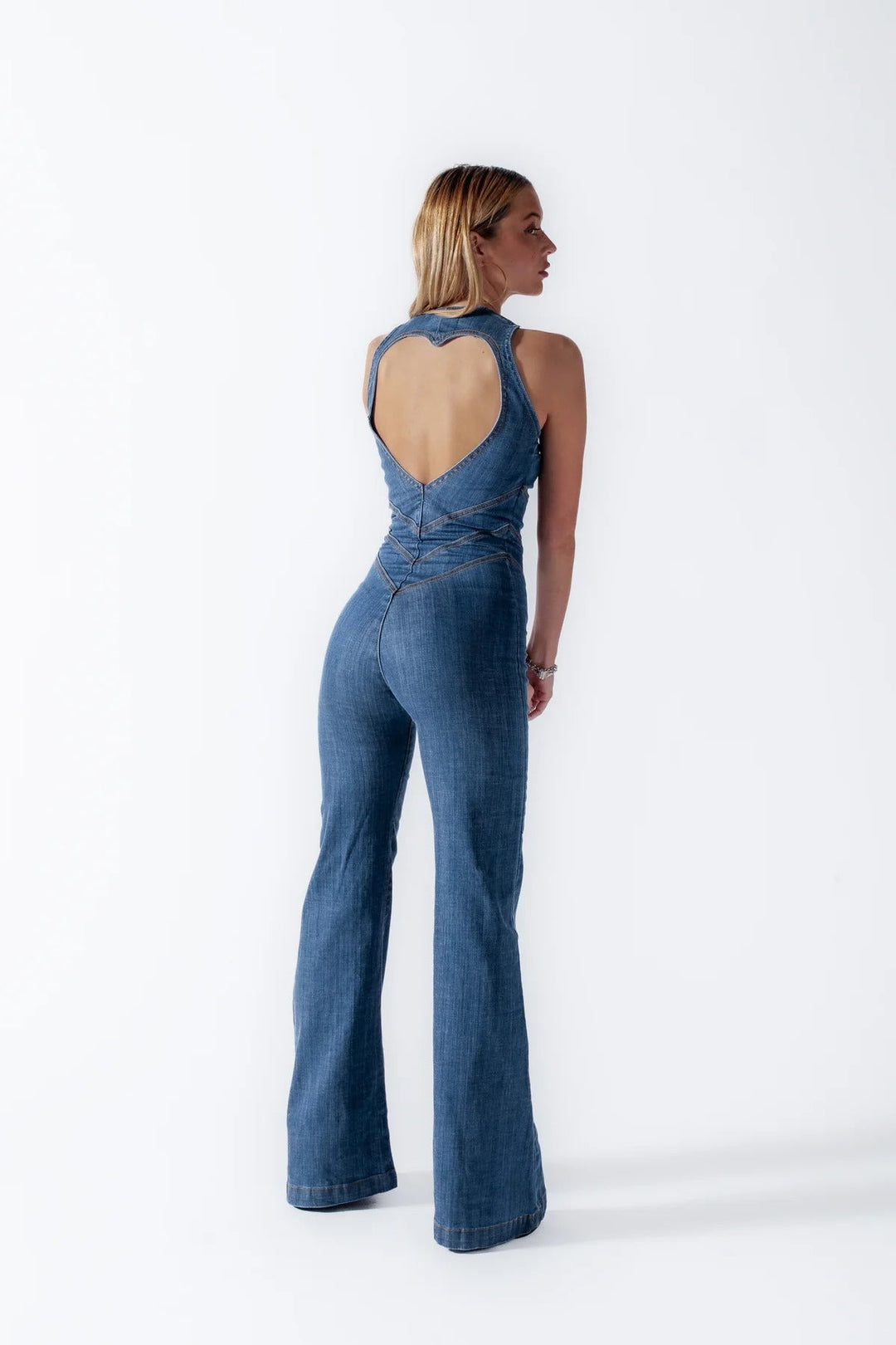 "Dunkelblauer Denim Damen-Overall, ärmellos, mit herzförmigem Rückenausschnitt und Vintage-Charme, vor weißem Hintergrund."