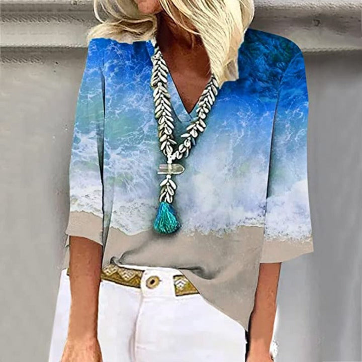Elegante, luftige Damenbluse mit kristallblauen Nuancen und sandigen Tönen, V-Ausschnitt und weiten Ärmeln.