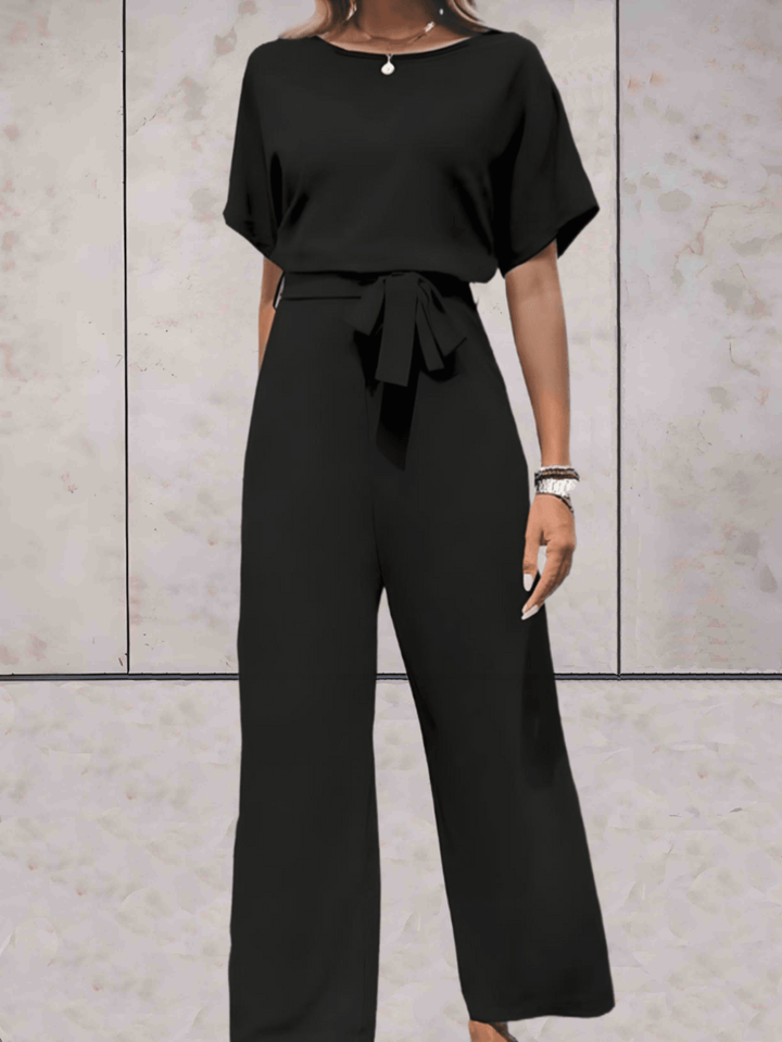 Eleganter Jumpsuit in Beige, schwarze Details, betont Silhouette, vielseitig für Tag und Abend, verfügbar in XS-2XL.