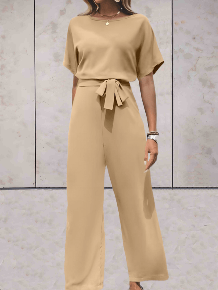 Eleganter Jumpsuit in Beige, schwarze Details, betont Silhouette, vielseitig für Tag und Abend, verfügbar in XS-2XL.