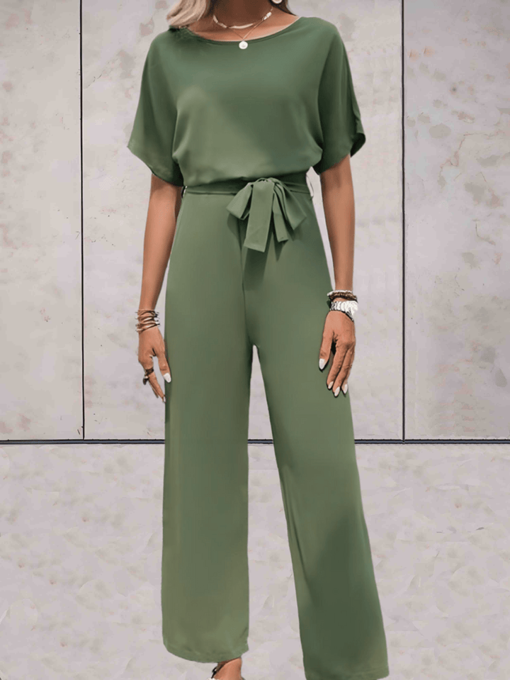 Eleganter Jumpsuit in Beige, schwarze Details, betont Silhouette, vielseitig für Tag und Abend, verfügbar in XS-2XL.