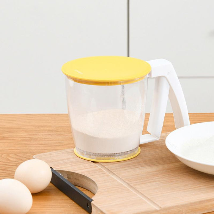 Handgehaltenes gelbes Mehlsieb für einfaches Einhandsieben, aus lebensmittelechtem Material, platzsparend und effizient.