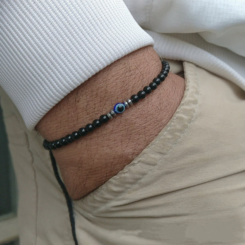 "Herren Armband aus 4 mm Naturstein mit Böse-Augen-Perle, stilvolles Schutzsymbol auf dunklem Hintergrund."