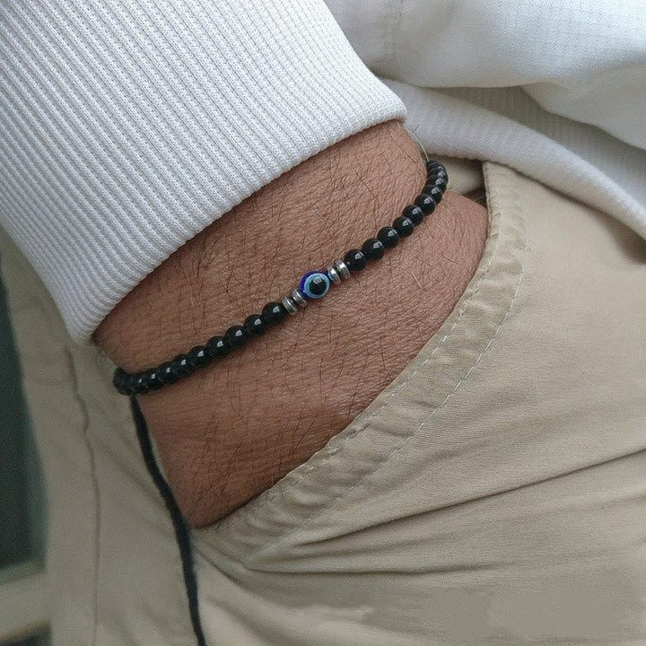 "Herren Armband aus 4 mm Naturstein mit Böse-Augen-Perle, stilvolles Schutzsymbol auf dunklem Hintergrund."