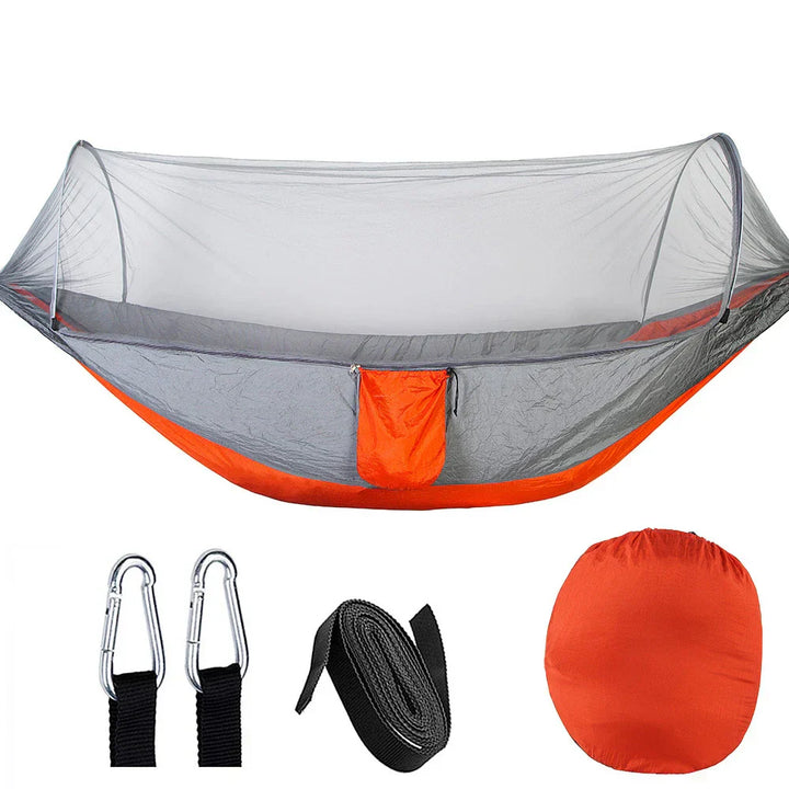 "Outdoor-Hängematte mit Moskitonetz, aus grünem Fallschirmstoff, hängend zwischen zwei Bäumen, ideal für Camping."