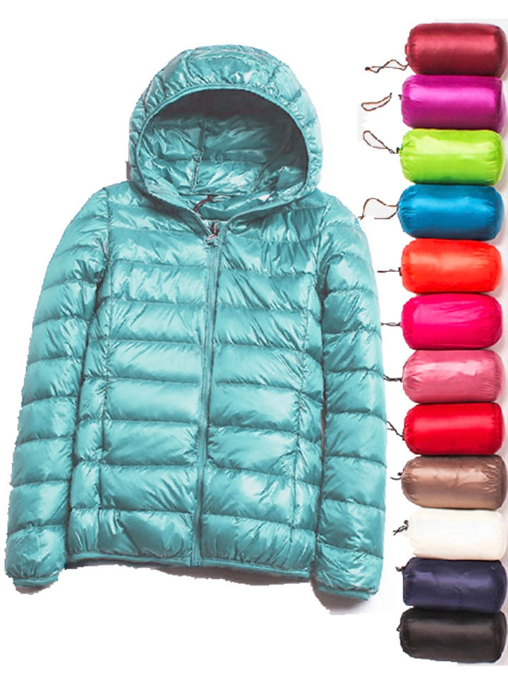 Ultraleichte blaue Damenjacke, wasserabweisend, Stil frontansicht mit verstellbarer Kapuze und praktischen Taschen.