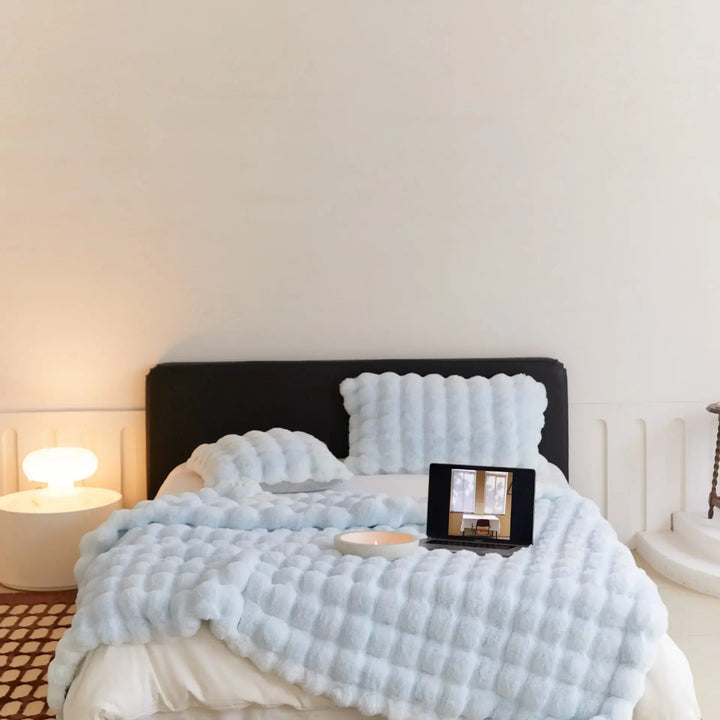Weiche Plüschwolldecke, kuschelig und stilvoll, in eleganten Farben für gemütliche Abende auf Sofa oder Bett.