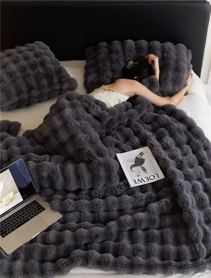 Weiche Plüschwolldecke, kuschelig und stilvoll, in eleganten Farben für gemütliche Abende auf Sofa oder Bett.